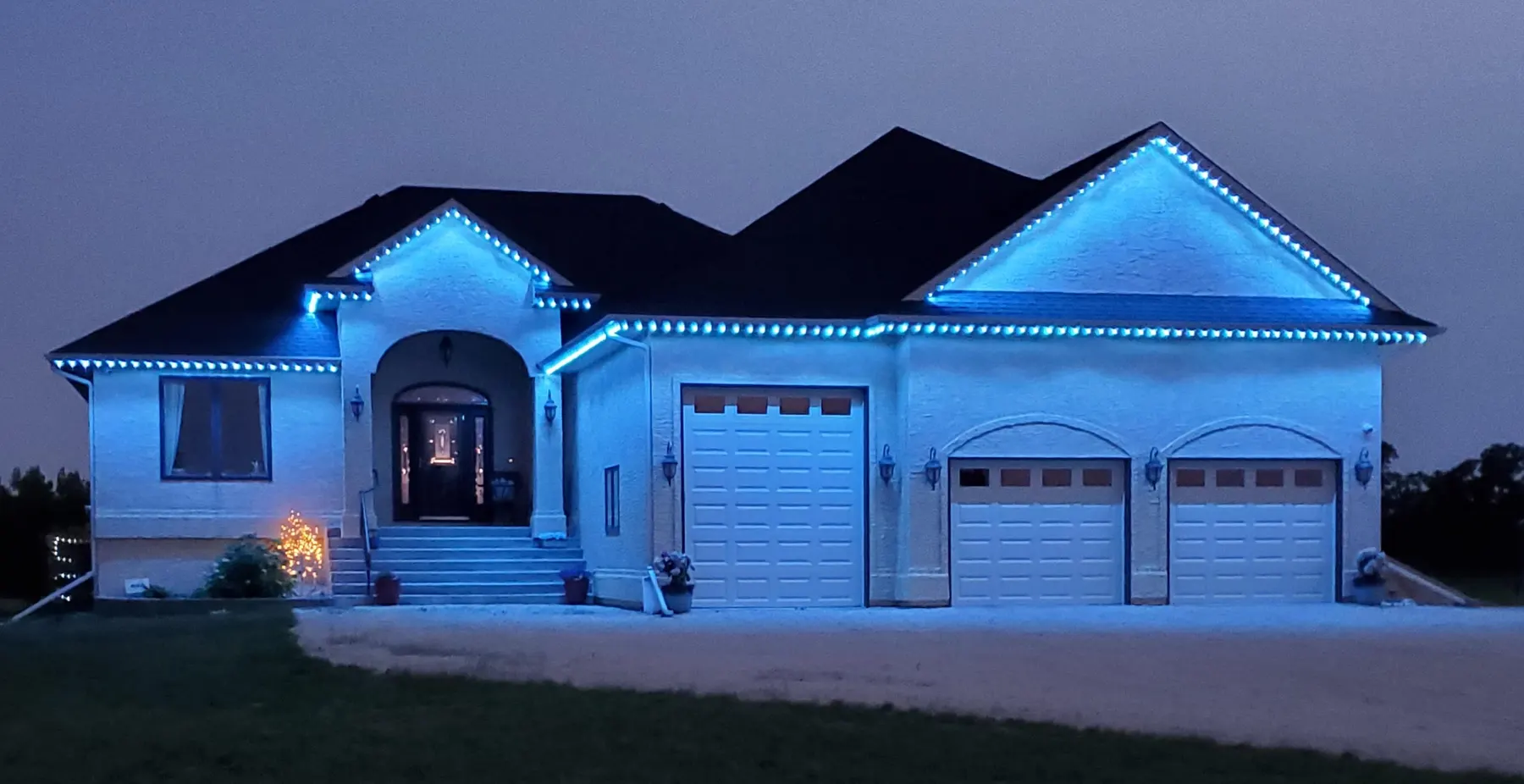 Bungalow lit in cool blue permanent roofline lights at dusk