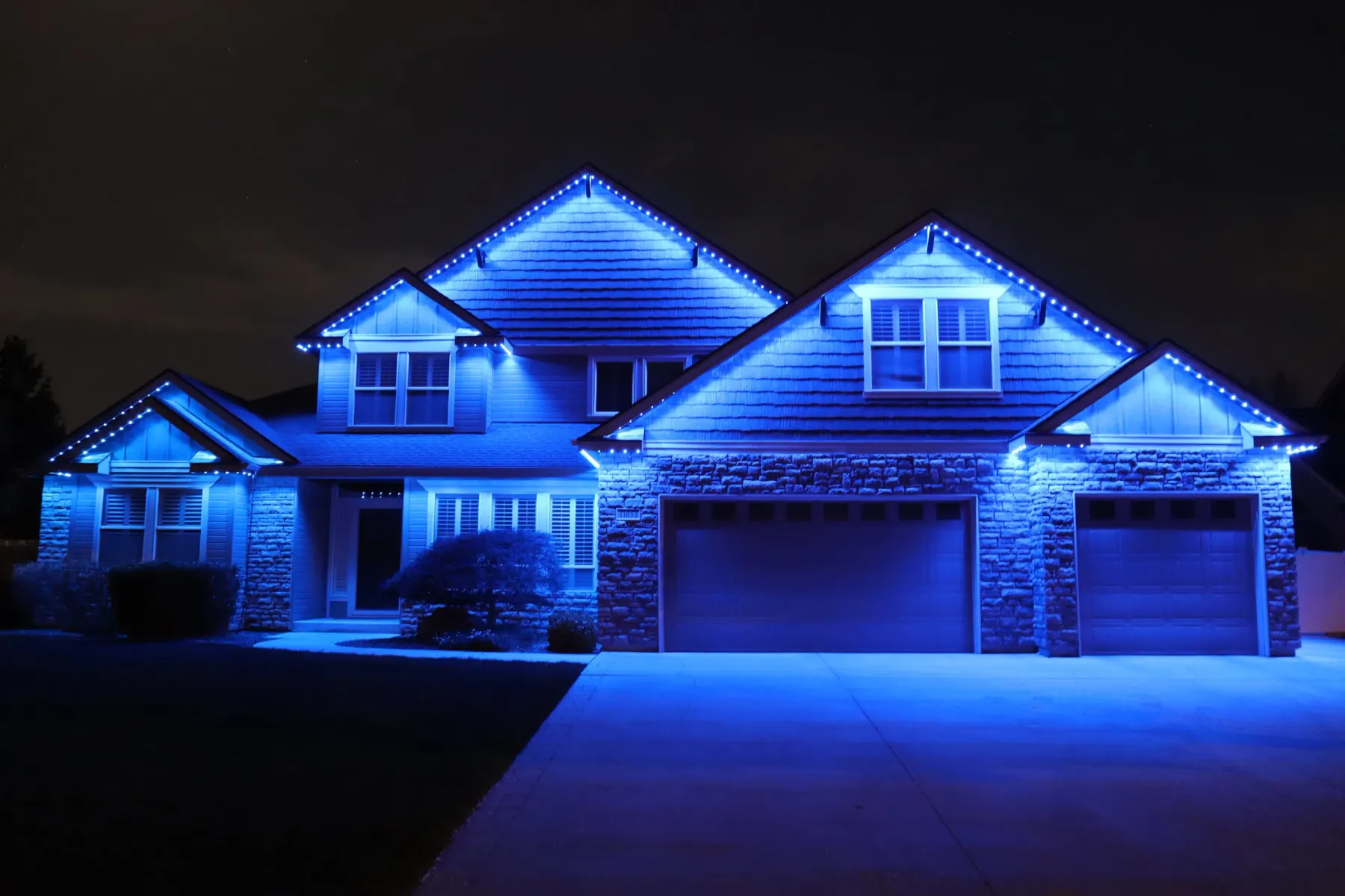 Blue permanent LED lights tracing every peak of a large home at night