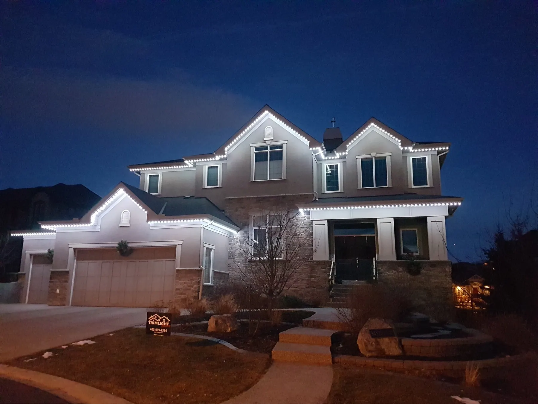 Warm white permanent lighting on a large two-storey home at night