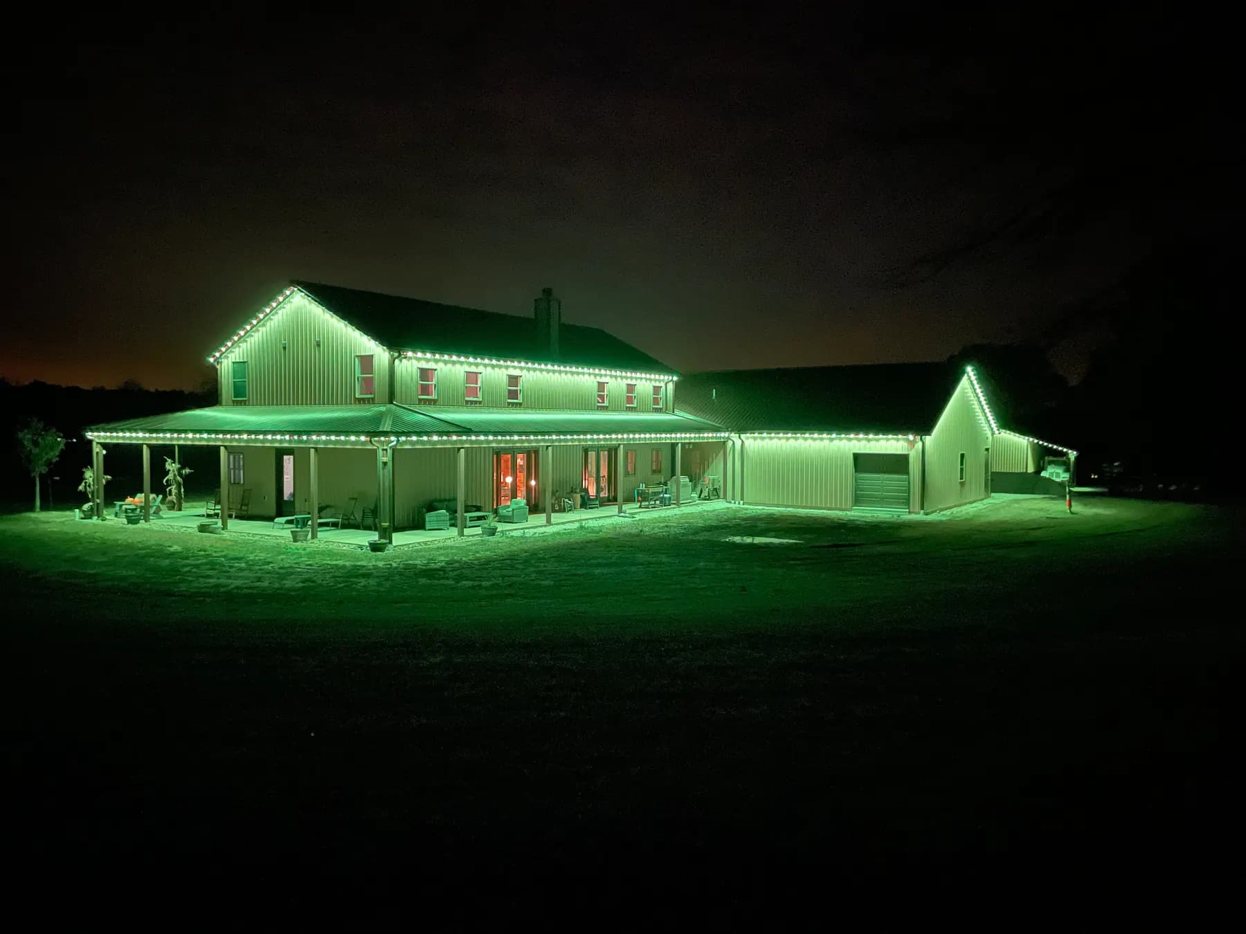 Green permanent LED roofline lights on a country home with a wide lawn