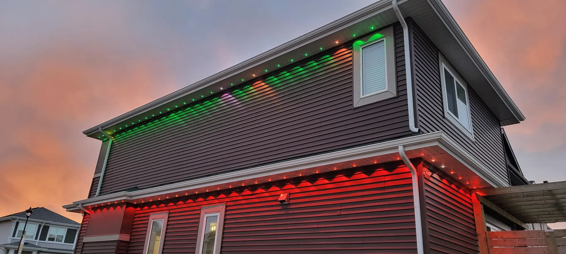 Side elevation of a home with red and green permanent lights at sunset