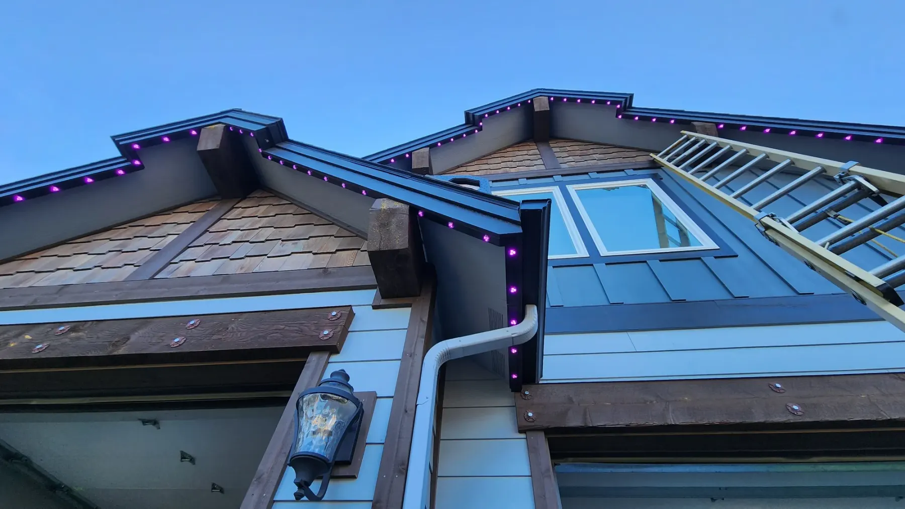 Homeowner checking a twist connector between two pieces of aluminum LED track along a roofline to diagnose a lighting issue